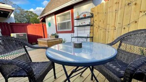 A round glass table with two wicker chairs on a wooden deck. - Boho Bungalow! Guesthouse near Downtown & Beaches!  (St. Petersburg)