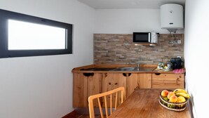 A compact kitchen with a wooden countertop, a built-in microwave, a sink, and a window.