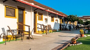 A row of white buildings with red roofs, outdoor seating, and a well-maintained lawn.