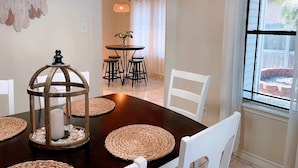 A dining area with a wooden table, woven placemats, and a decorative birdcage centerpiece. - Padre Island house with private pool (Corpus Christi)