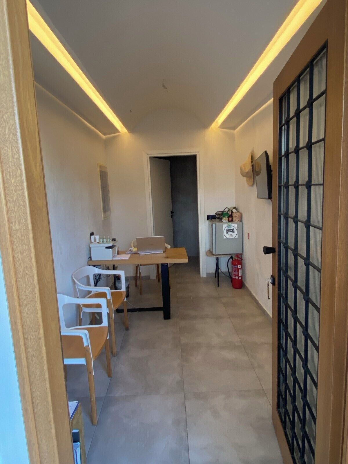 A hallway with a dining area featuring a table and chairs, a small kitchenette, and a fire extinguisher.