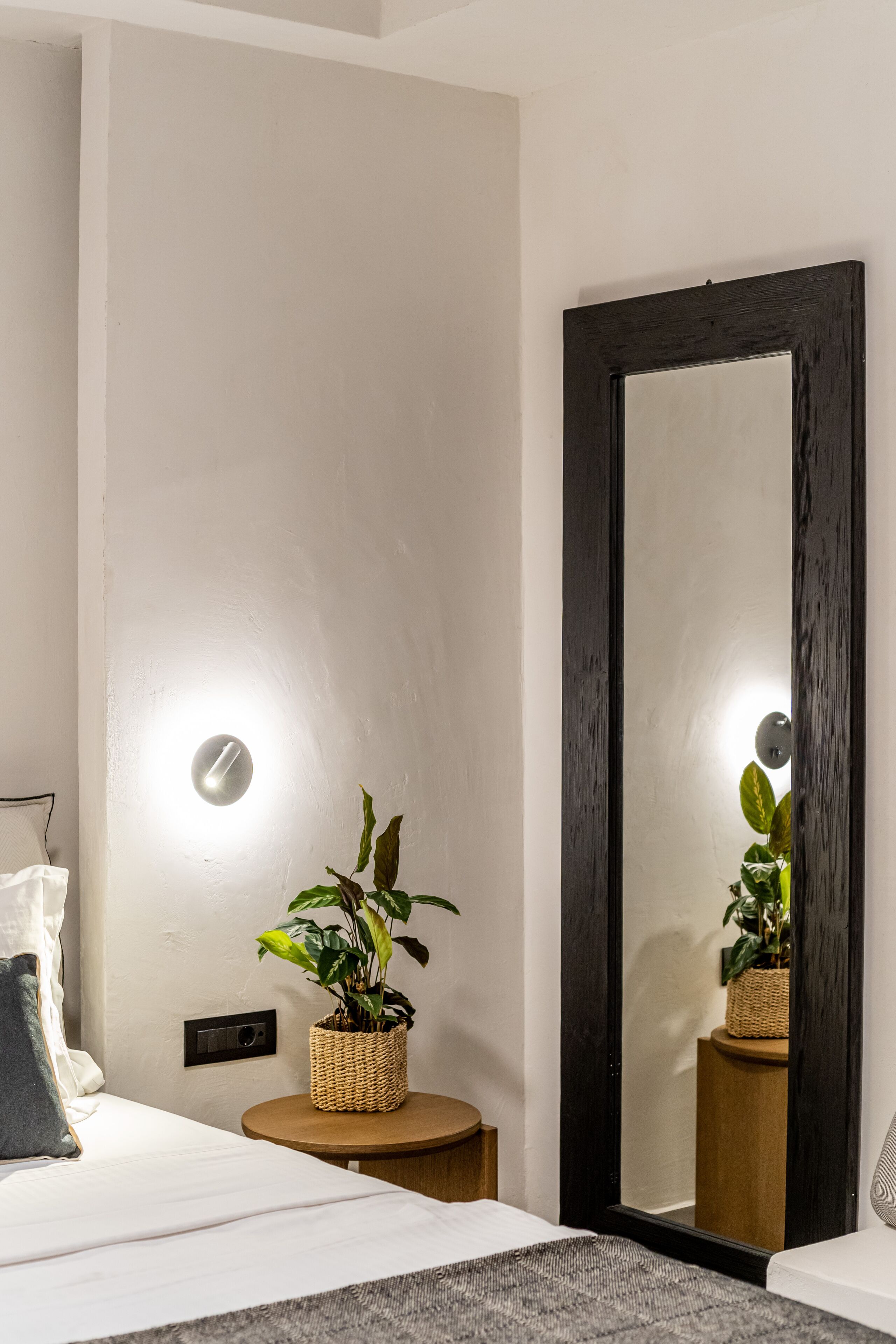A modern bedroom with a bed, bedside table, and a large mirror.