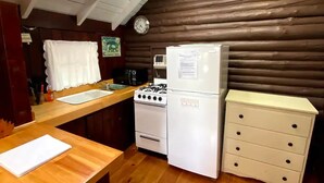 Una cocina con encimera de madera, estufa, refrigerador y un reloj en la pared.