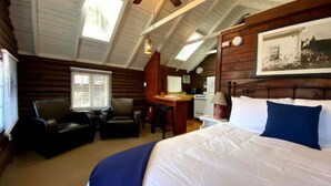 Acogedora habitación tipo cabaña de madera con una cama grande, un escritorio y una silla.