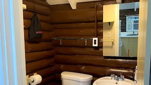 Un baño pequeño con inodoro, lavamanos y paredes de madera.