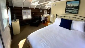 Una habitación con una cama grande, un escritorio, una silla y una ventana con persianas.