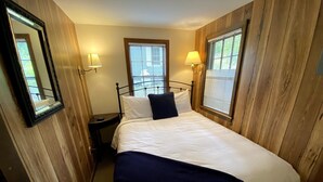 Un dormitorio con una cama, dos lámparas de noche, un ventanal con persianas y paneles de madera.