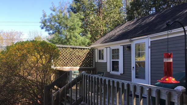 A residential property with a wooden deck, a covered porch, and a red bird feeder.
