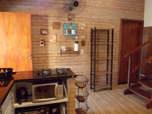 Eine Küche mit Backsteinwand, einer Mikrowelle, einer Kaffeestation und einer Holztreppe.