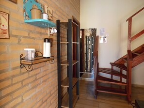 Eine Treppe führt zu einer zweiten Etage, eine Ziegelwand mit Regalen für Küchenutensilien und ein Holzboden.