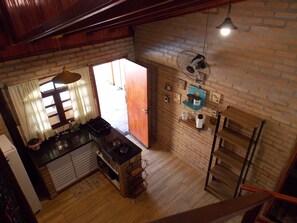 Cozinha com bancada de madeira, pia e janela com cortinas.