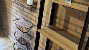 A brick wall with shelves, a metal chair, and a coffee machine.