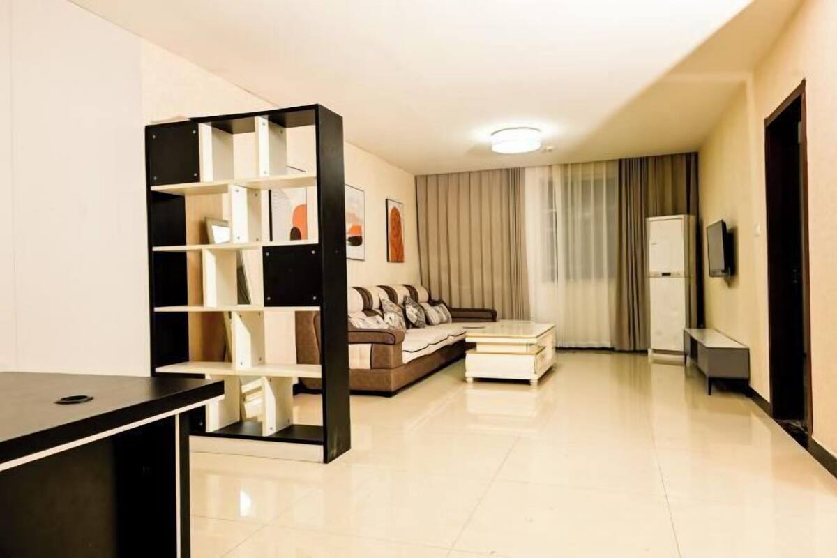 A modern living room with a sofa, a coffee table, and a bookshelf.