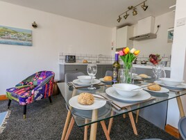 Comedor con mesa de vidrio, sillas y un banco acolchado de colores.