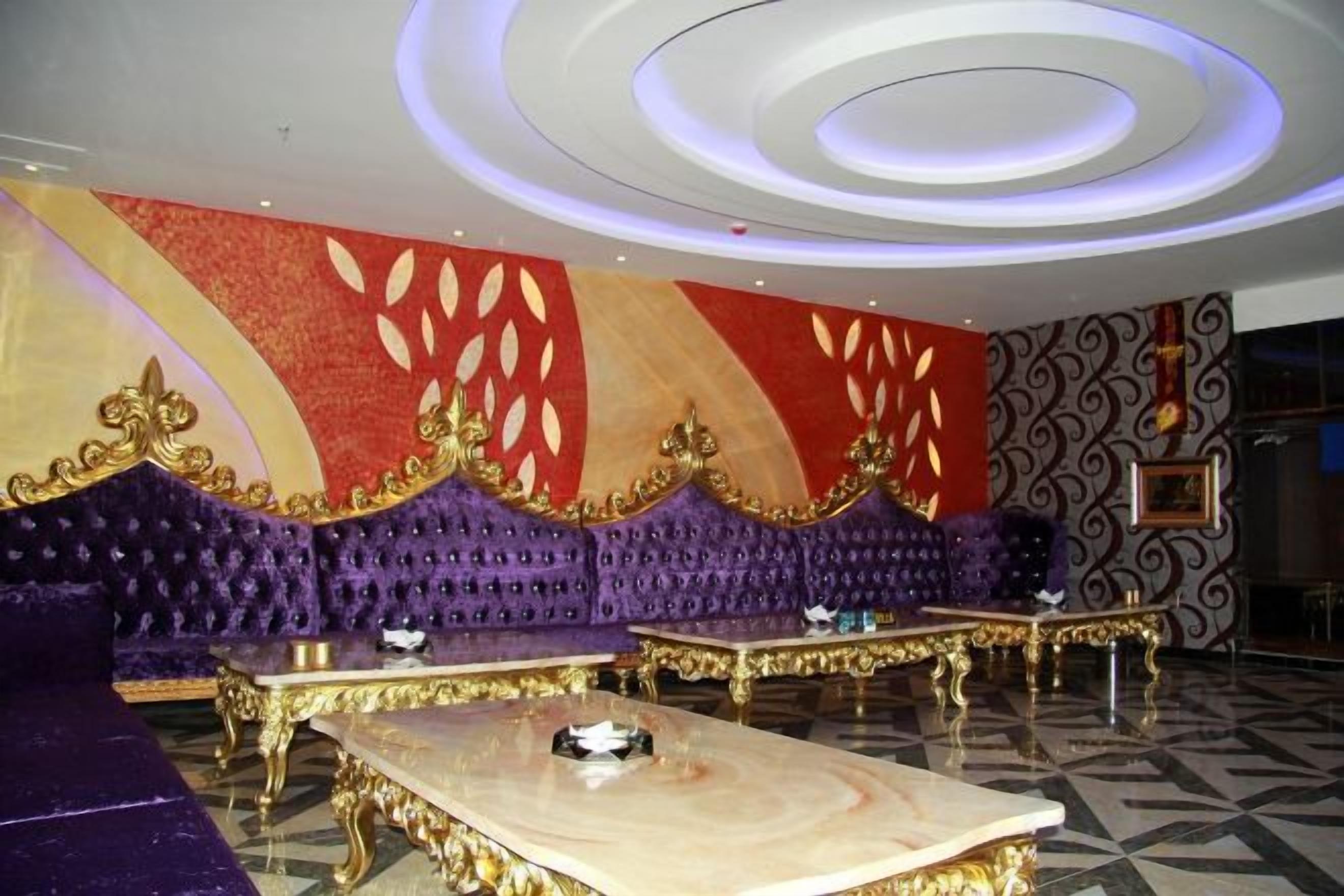 Una habitación lujosa con un sofá morado, detalles dorados y una mesa de mármol.