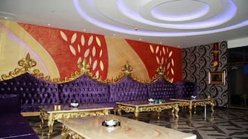 Una habitación lujosa con un sofá morado, detalles dorados y una mesa de mármol.