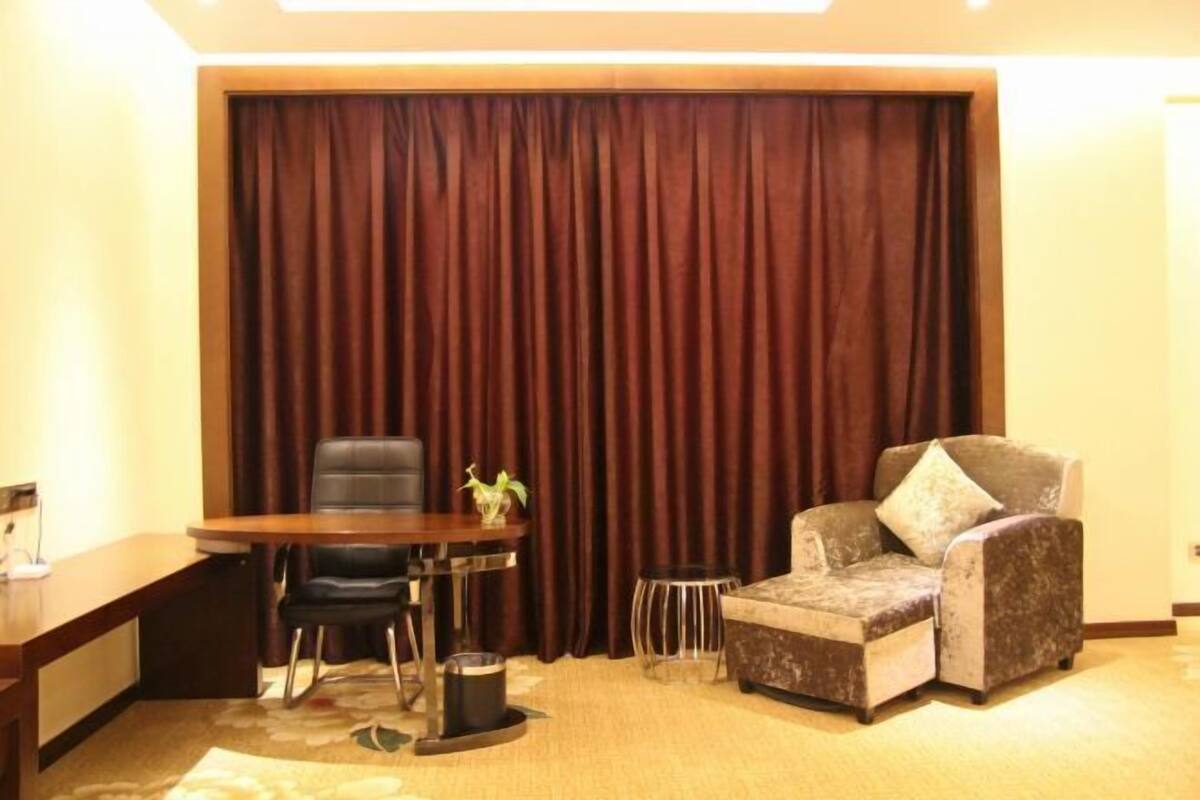 Een kamer met een houten bureau, twee stoelen, een klein bijzettafeltje en een bank.