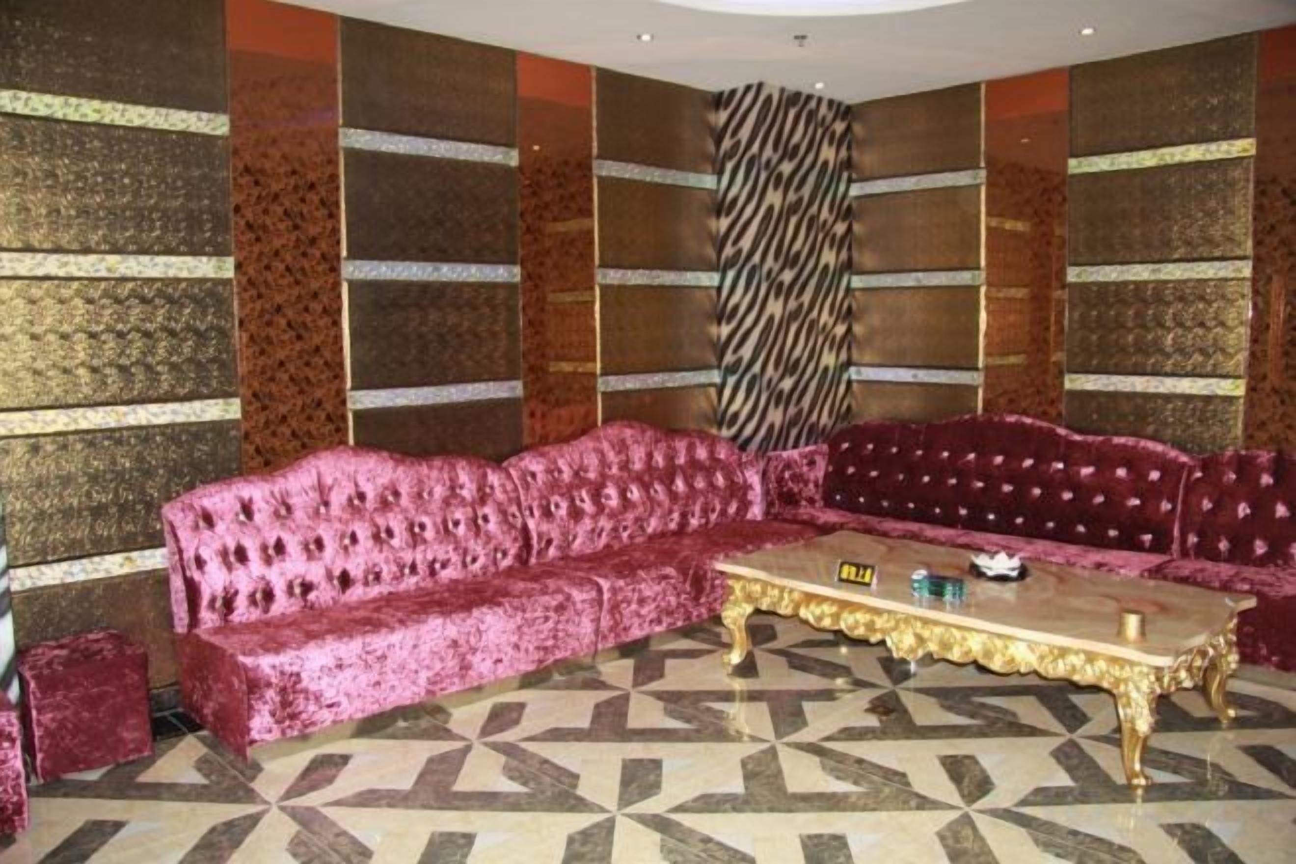 Una habitación con piso estampado, un sofá rosa grande y una mesa de centro con marco dorado.