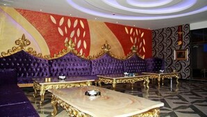 A luxurious lobby with a purple velvet sofa, gold-accented furniture, and a red and gold patterned wall.
