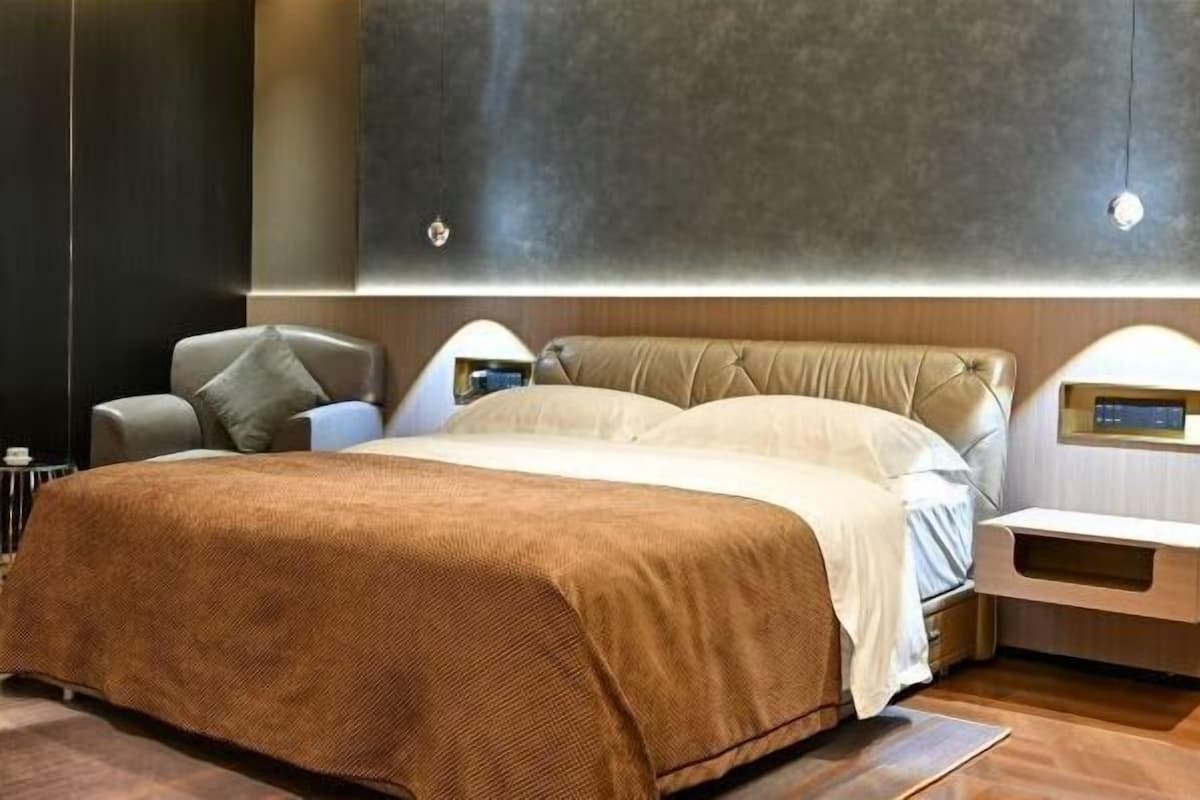 Een moderne hotelkamer met een groot bed, een nachtkastje, een stoel en een tv aan de muur.
