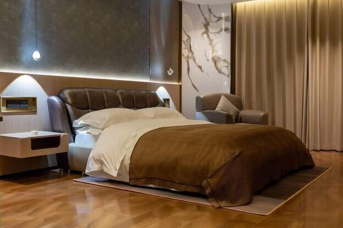 Een moderne slaapkamer met een groot bed, een nachtkastje, een wandplank en een gordijn.