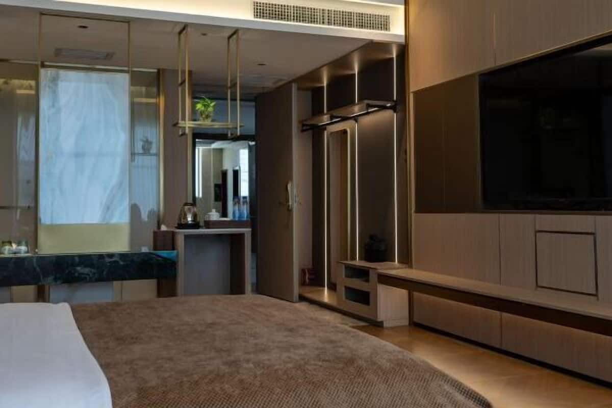 Een moderne hotelkamer met een groot bed, een flatscreen televisie, een ingebouwd bureau en een zithoek met televisie.