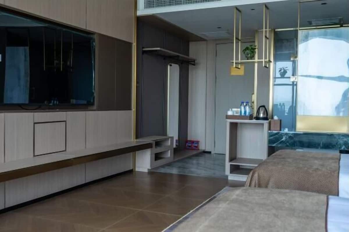 Een moderne hotelkamer met een groot raam, een ingebouwde televisie, een kleine kitchenette en een bed met uitzicht.