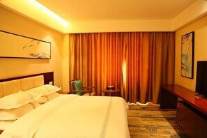 A hotel room with a large bed, a chair, a small table, and a TV on a stand. - Li Hou Hotel (Licheng)