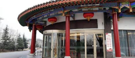 A traditional building with a curved entrance, red pillars, and a glass door.
