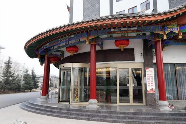 A traditional building with a curved entrance, red pillars, and a glass door. - Li Hou Hotel (Licheng)