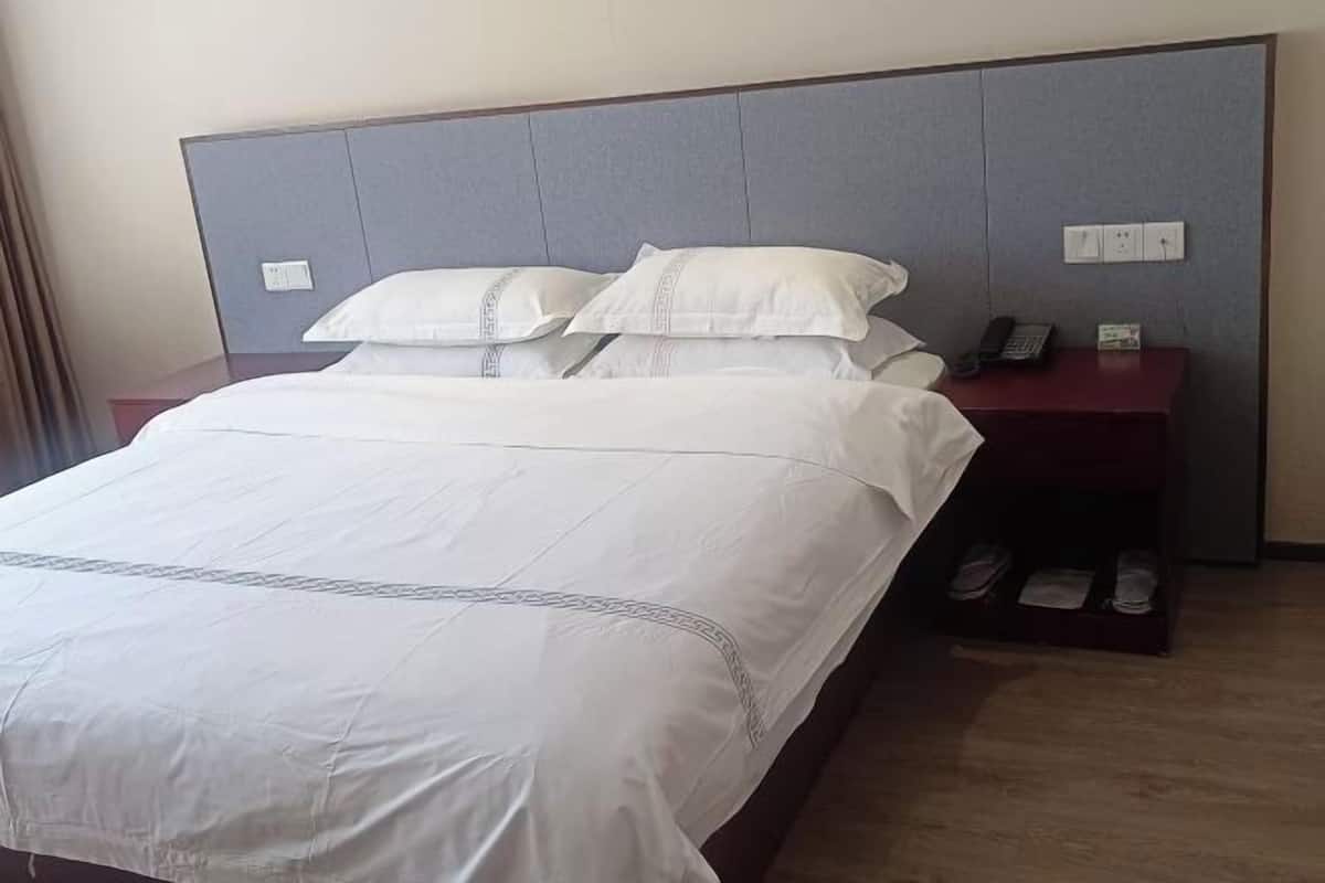 Une chambre d’hôtel avec un lit, une table de chevet avec un téléphone et un porte-chaussures.