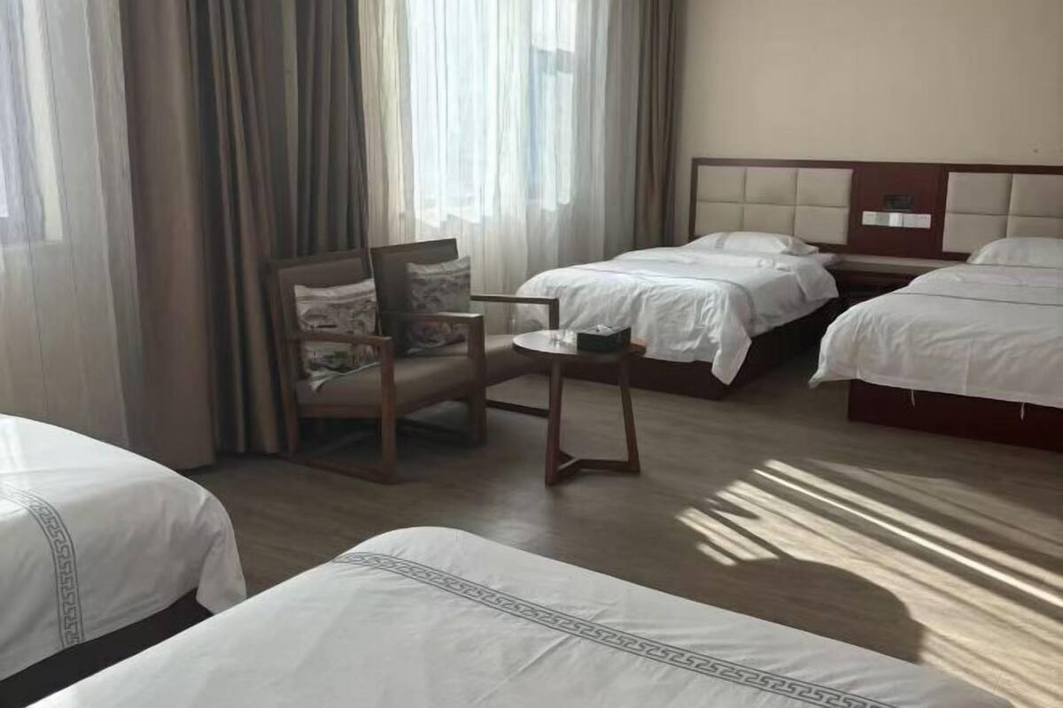 Une chambre d’hôtel avec deux lits, une chaise et une fenêtre avec des rideaux.