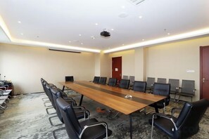 Un salón de conferencias con una larga mesa, varias sillas y piso alfombrado.