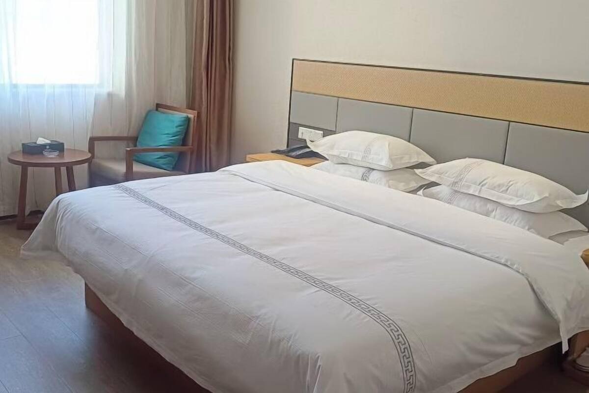 Une chambre d’hôtel avec un grand lit, une table de chevet, une chaise et une petite table.