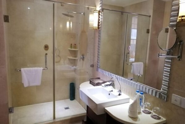 Une salle de bain moderne avec une douche à parois de verre, un lavabo blanc et un grand miroir.