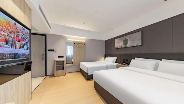 Habitación de hotel con televisión, dos camas, escritorio y un pequeño rincón de descanso.