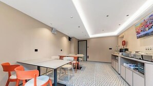 Una habitación de hotel moderna con comedor, cocina y una gran pantalla de televisión.