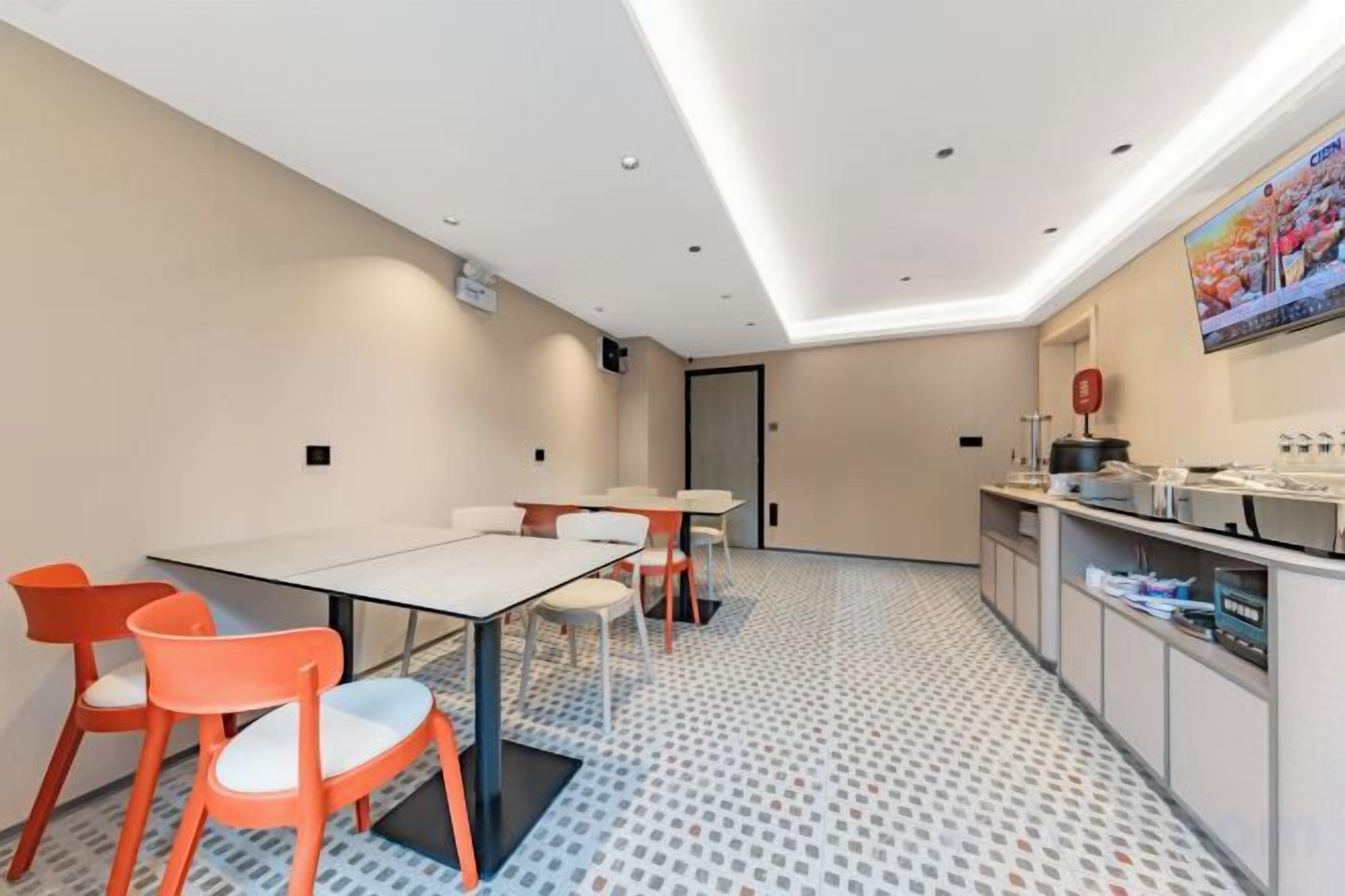 A modern hotel room with a dining area, a kitchen, and a patterned floor.