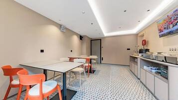 A modern hotel room with a dining area, a kitchen, and a patterned floor.