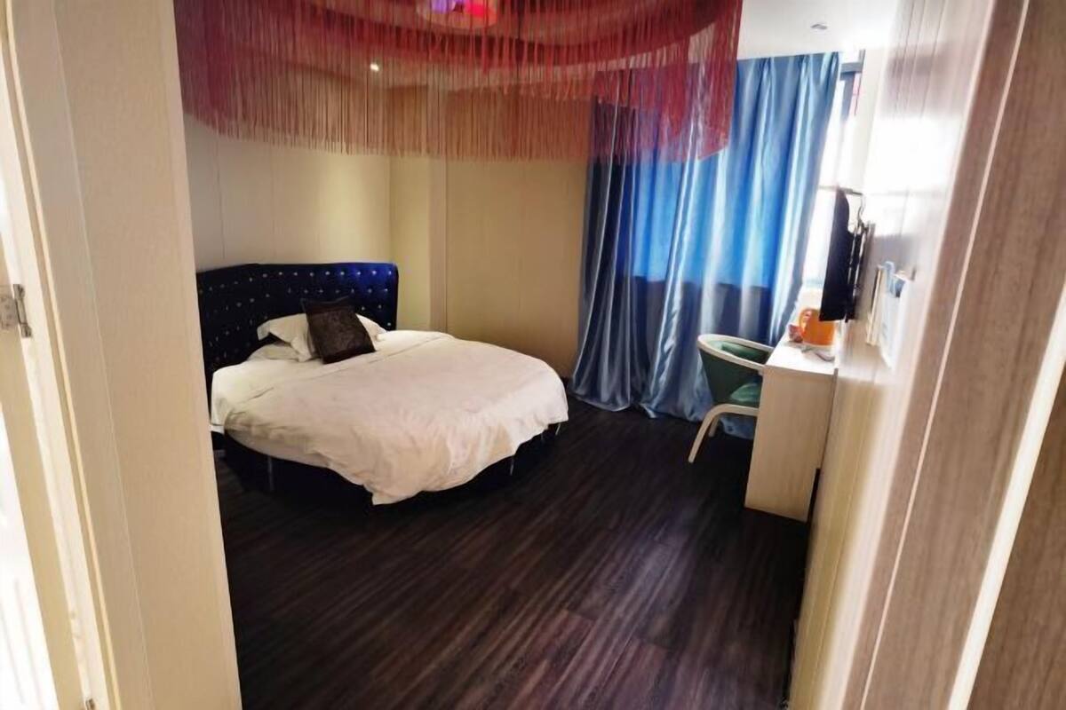 Quarto de hotel com uma cama, uma escrivaninha e uma cadeira.