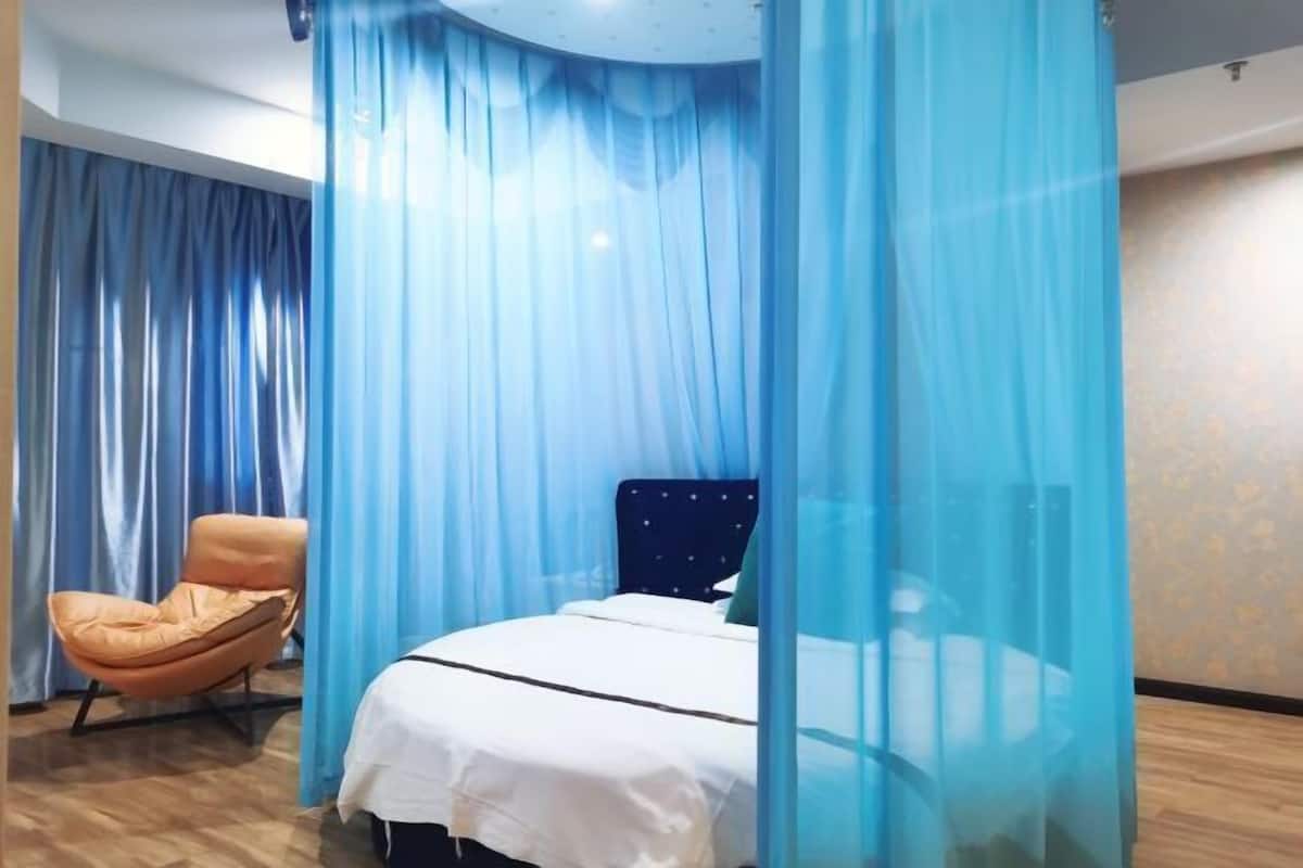 Um quarto com uma cama, uma cadeira e um dossel.