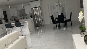 Una cucina moderna con mobili bianchi, un frigorifero in acciaio inossidabile e un'area pranzo con tavolo e sedie neri.