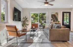 Relax in this spacious living room with a sofa, chair, and coffee table, offering a comfortable seating area and access to an outdoor space via the staircase.