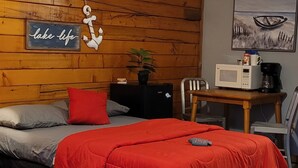 A room with two beds, wooden walls, a ceiling fan, a microwave, and a coffee maker on a wooden table. - Fun In The Sun #11 (Karnack)