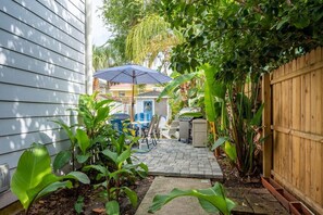 A backyard with a patio, a grill, and a wooden fence.
