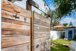 A wooden fence with a street sign, a white shed, and a lawn chair.