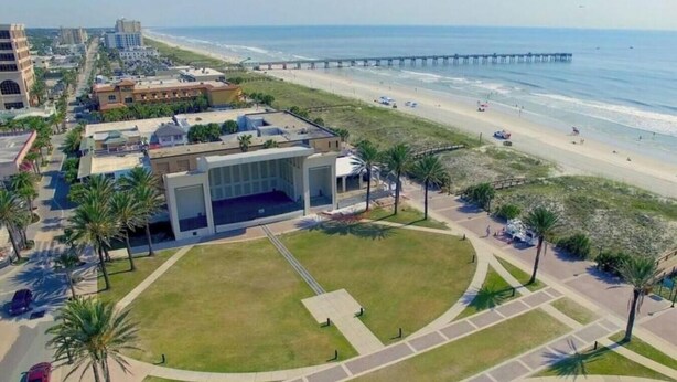 An aerial view of a coastal area with a modern building, a beach, and a pier. - 1/2 Mile to Beach, 2 bedroom townhome close to Mayo Clinic (Jacksonville Beach)