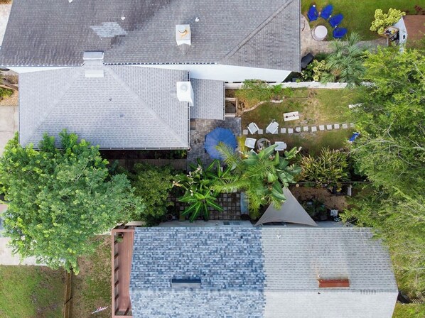 An aerial view of a residential property with a sloped roof, a small garden area with plants and a seating area, and a visible chimney.