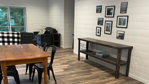 A modern kitchen with a wooden dining table, black chairs, and a marble countertop. - Hidden Hideway, fully furnished home perfect for family get aways! (Boyne City)