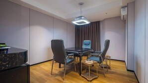 Una sala de conferencias moderna con una mesa de vidrio, cuatro sillas, un escritorio negro y una lámpara colgante.